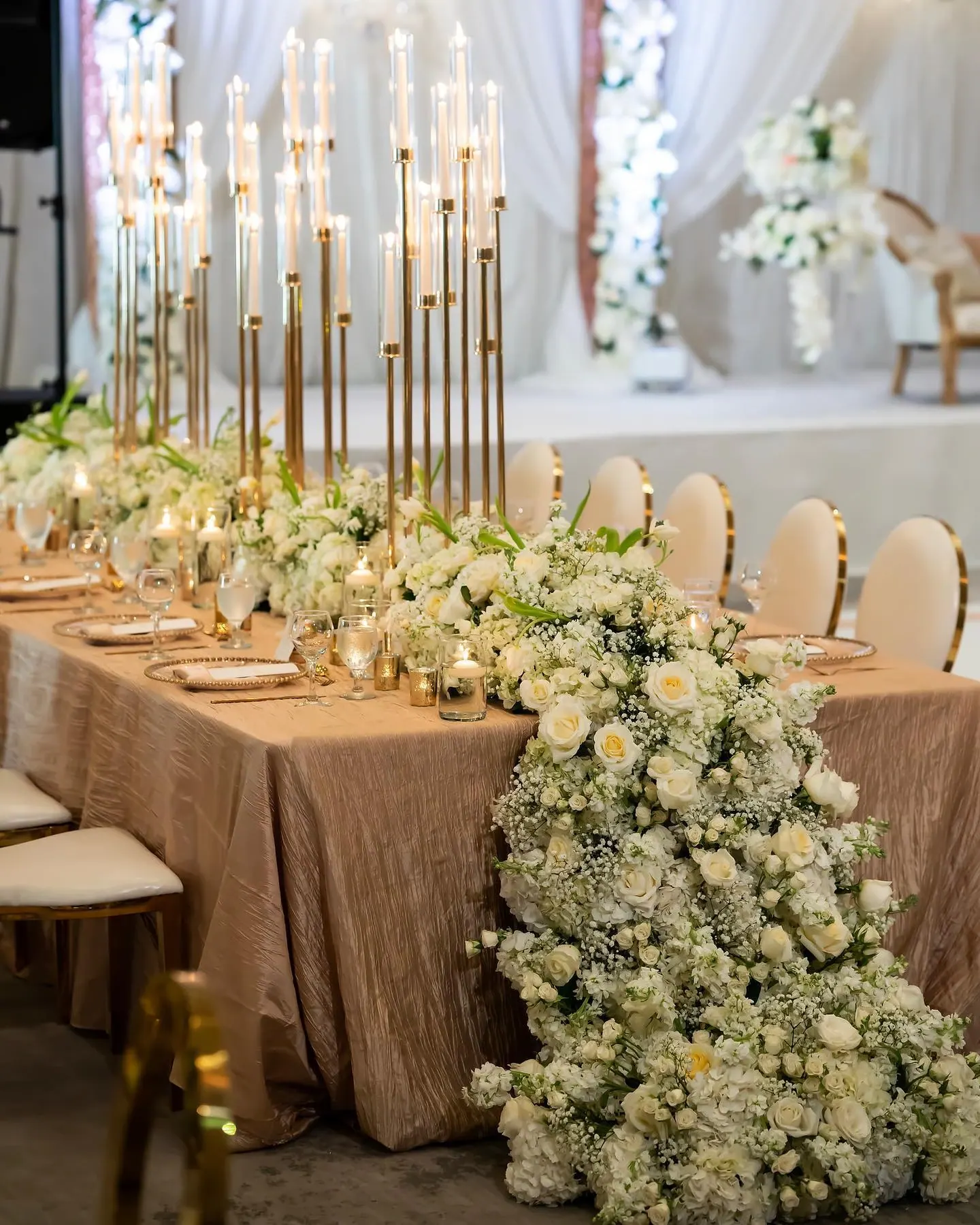 Long head table with cascading white floral runner and candelabra