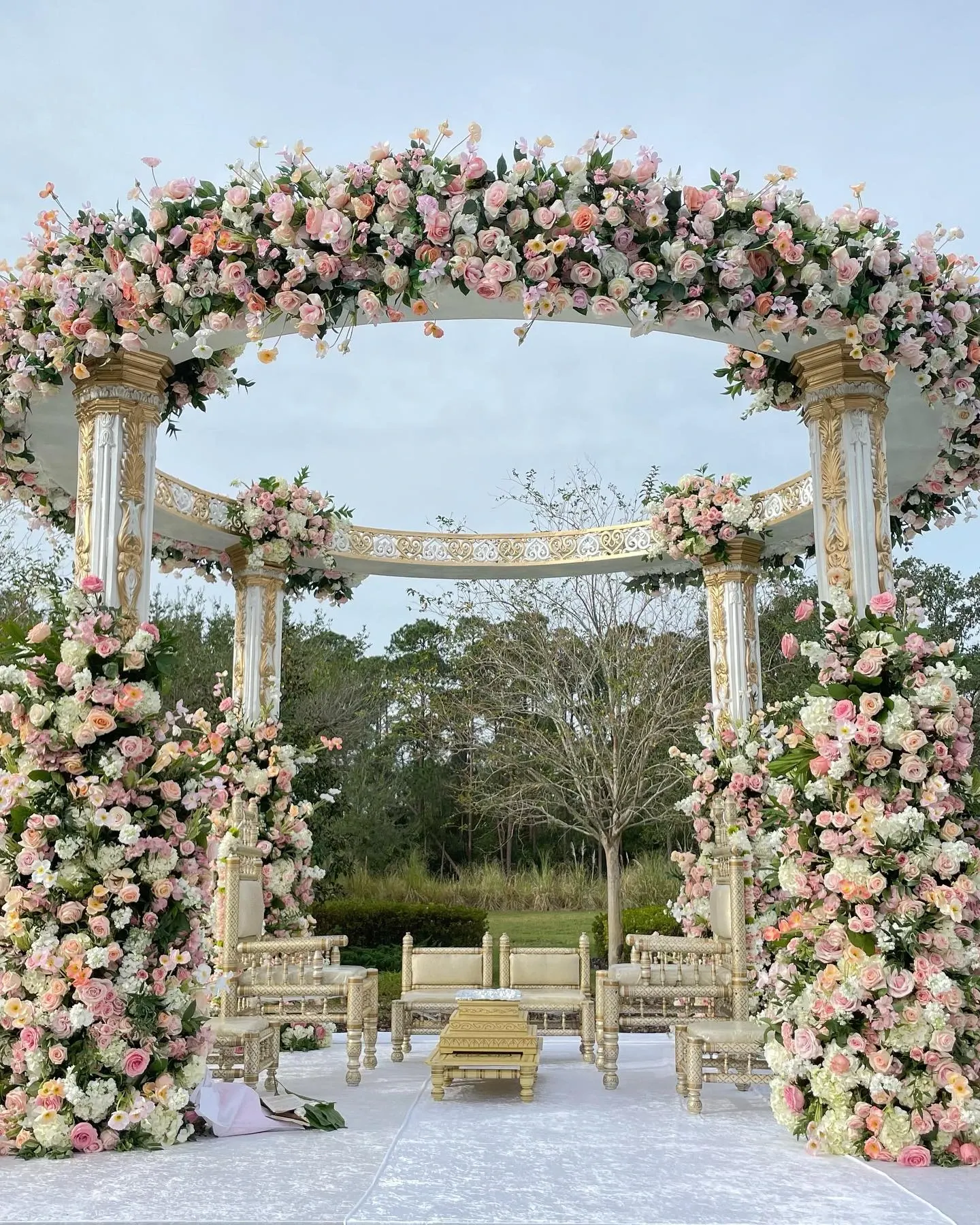 Outdoor mandap with cascading blush rose pillars and gold columns