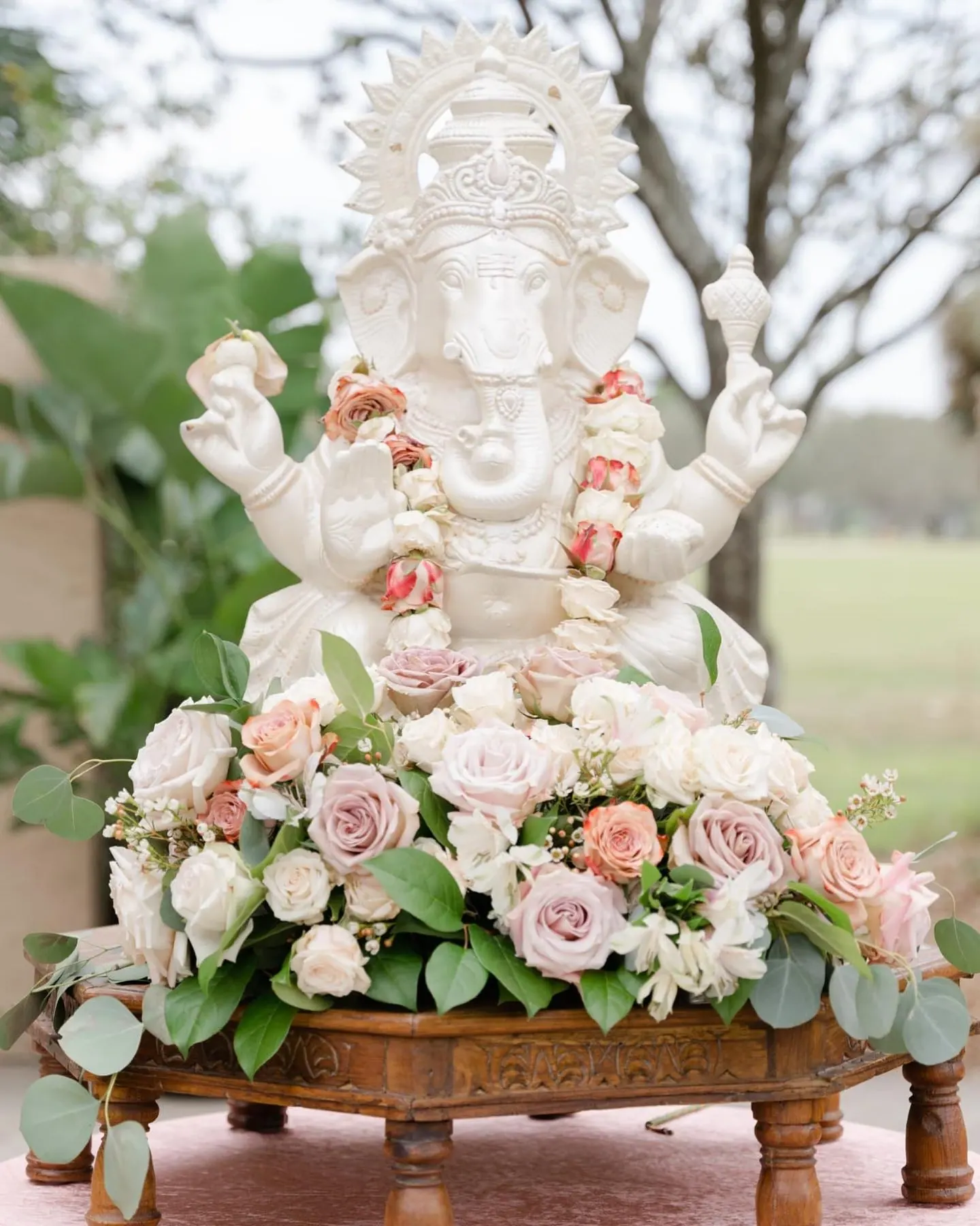 Ganesha shrine with blush roses and eucalyptus garland