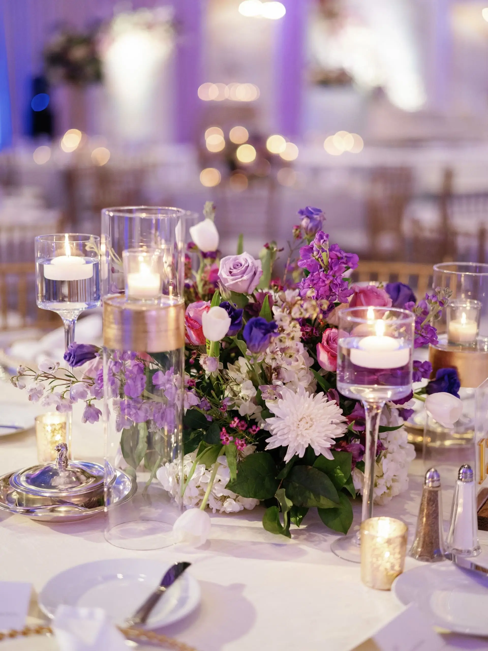 Long banquet table beneath suspended greenery and pendant lights